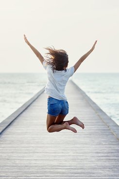 Rückansicht eines springenden Mädchens auf dem Pier mit Verlinkung zum 500 Euro Gewinnspiel.
